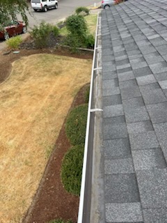 A clean white gutter line along a shingled roof after service