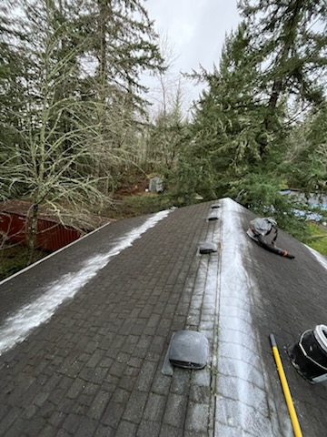 A residential rooftop mid-job with tools out, vents and ridge being cleared